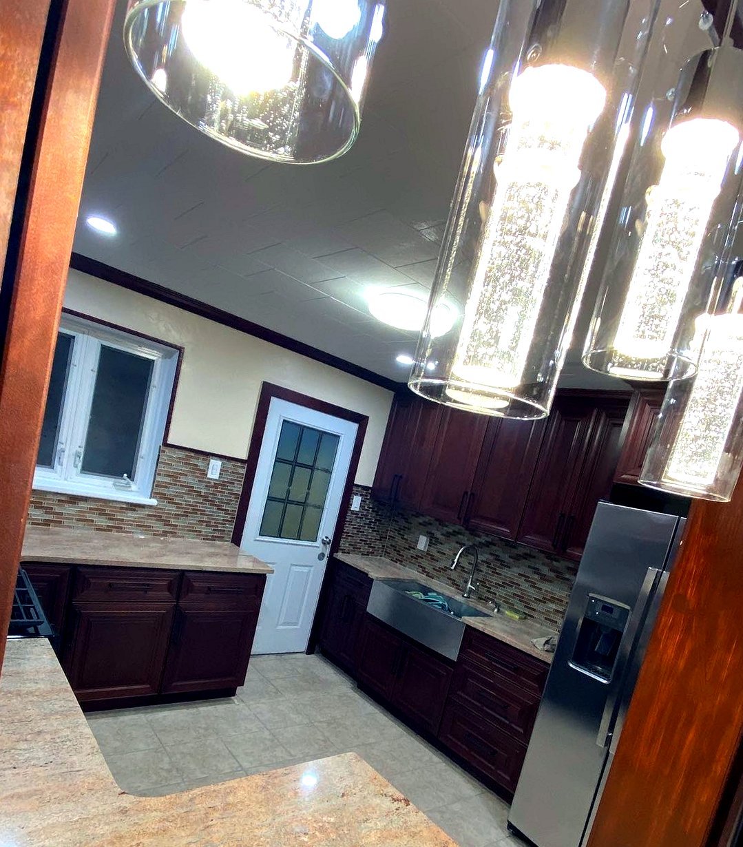 After: finished kitchen with cherry cabinetry, pendant lighting, and stainless appliances