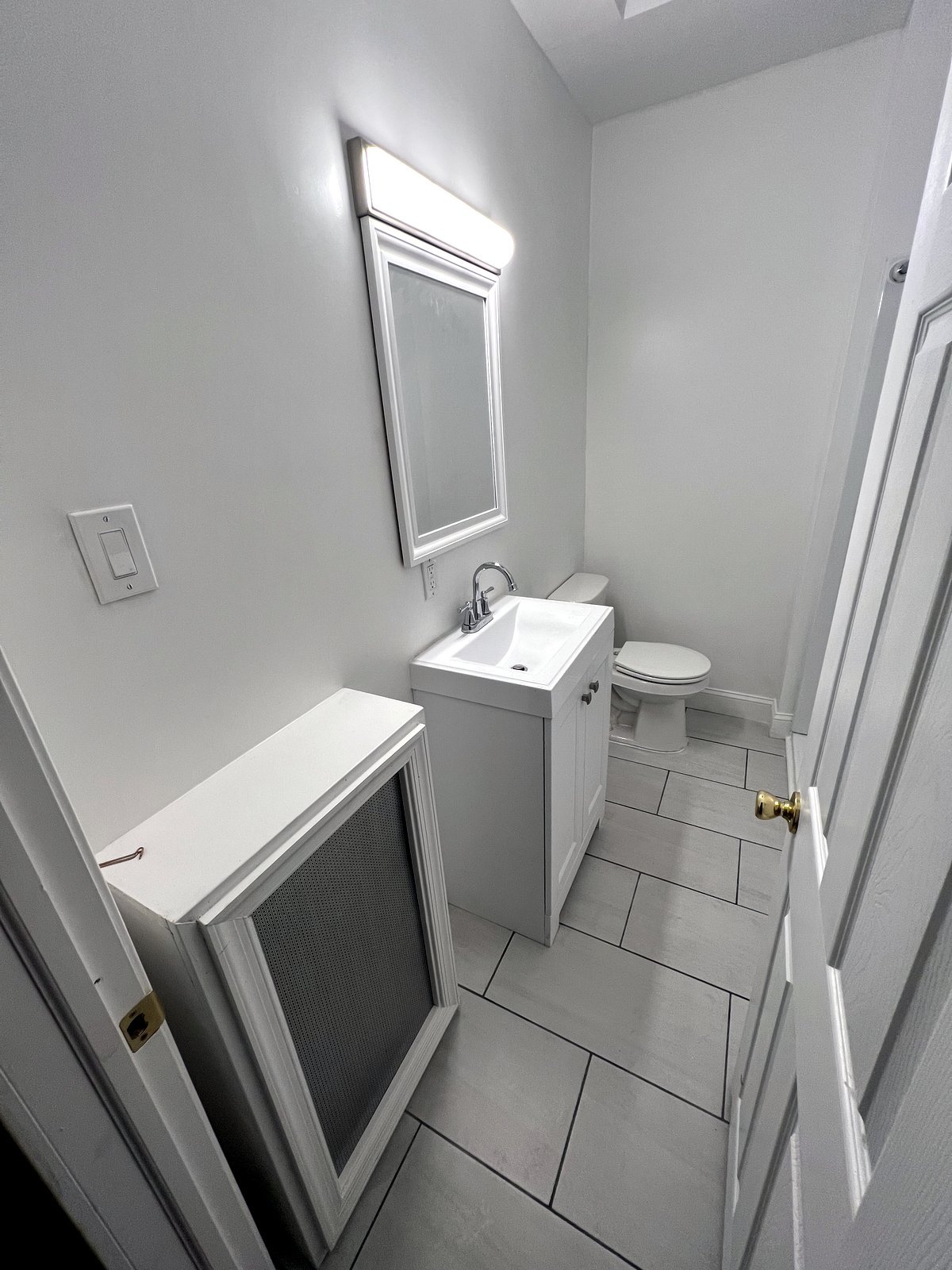 After: finished bathroom with navy vanity, marble-look tile floor, and glass shower door