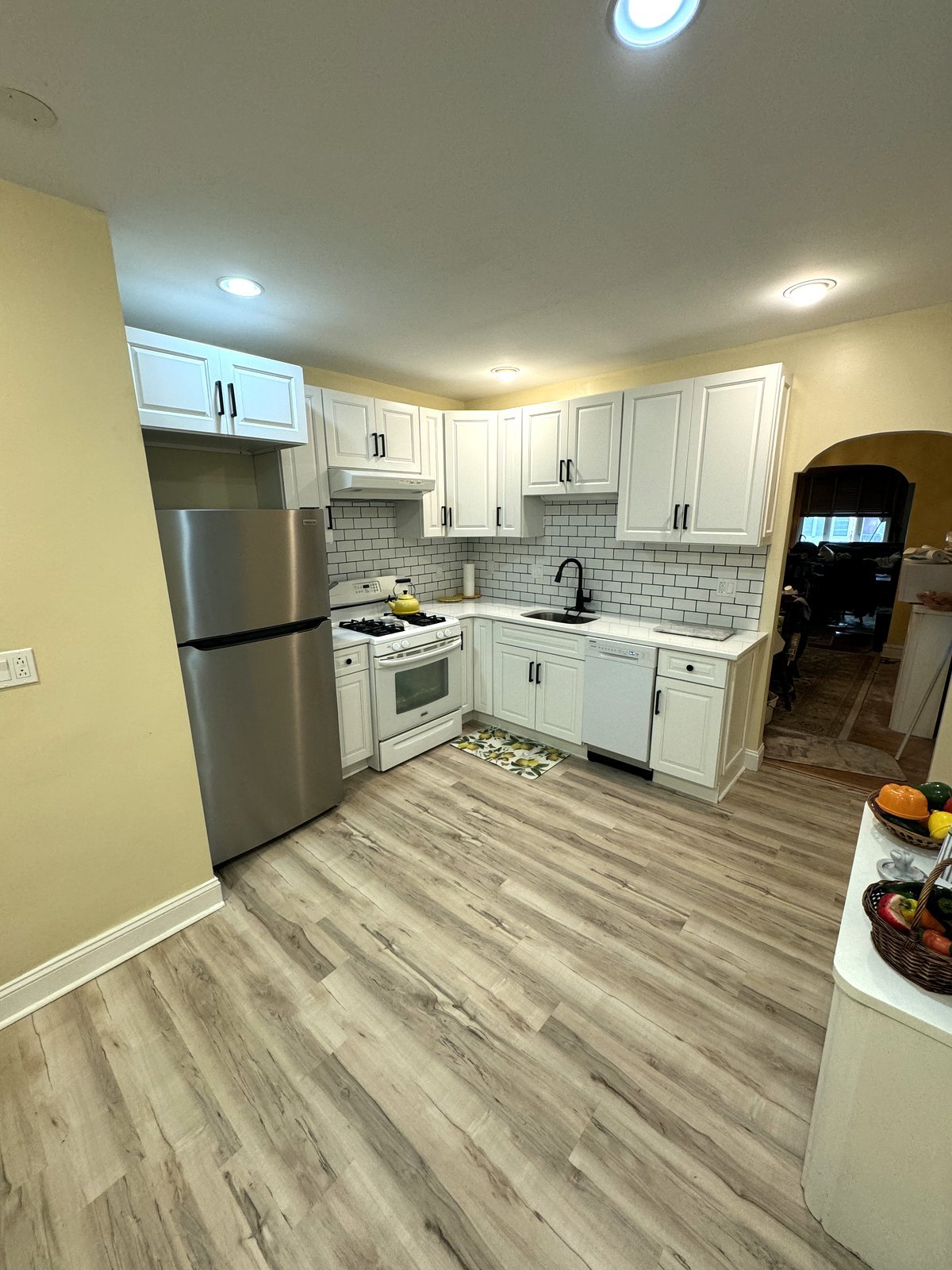 Renovated kitchen with white cabinetry, subway tile backsplash, and new appliances