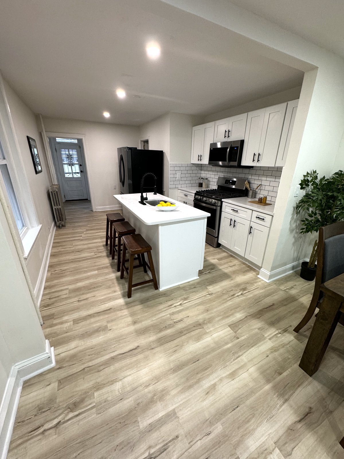 Renovated open kitchen with white cabinetry, quartz island, and new flooring