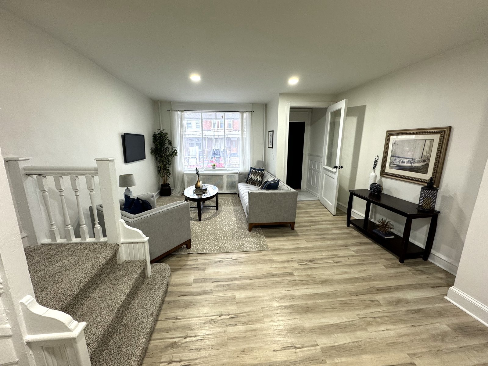Renovated living room with new flooring, staircase, and furnishings