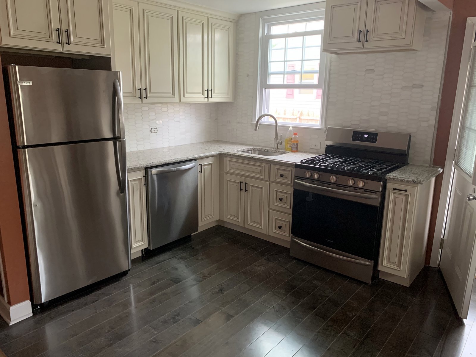 Finished kitchen with cream cabinets, stainless steel appliances, and dark wood floors